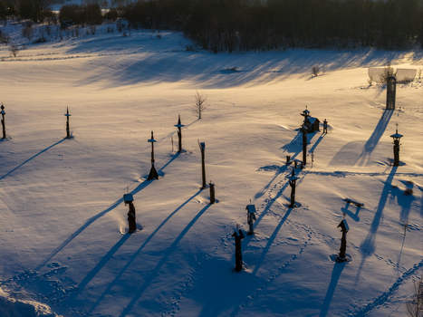 Aerial view of the Hill of Angels featuring tall wooden sculptures and long shadows across a snow covered field in Traku rajonas Vilniaus apskritis Lithuania. Aerial view of the Hill of Angels featuring tall wooden sculptures and long shadows across a snow covered field in Traku rajonas Vilniaus apskritis Lithuania.