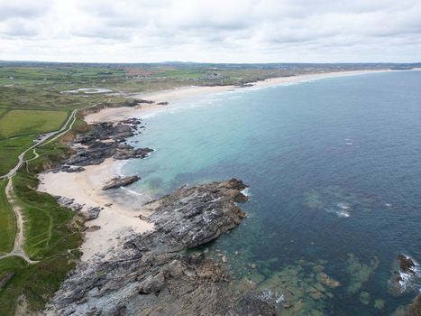 Aerial view of Godrevy Beach with its sandy shores dark rocky formations and turquoise Atlantic waters under a cloudy sky Gwithian England United Kingdom. Aerial view of Godrevy Beach with its sandy shores dark rocky formations and turquoise Atlantic waters under a cloudy sky Gwithian England United Kingdom.
