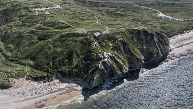 Aerial view of Bulbjerg a limestone cliff on the North Sea coast with grassy slopes walking paths and a historic bunker in Thisted Municipality Denmark. Aerial view of Bulbjerg a limestone cliff on the North Sea coast with grassy slopes walking paths and a historic bunker in Thisted Municipality Denmark.