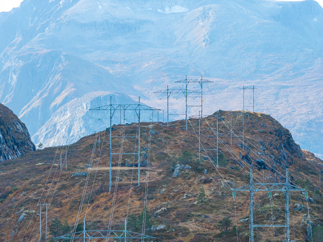 Aerial view of high voltage power lines stretching across a rugged rocky mountain landscape with sparse vegetation and distant peaks in Andalsnes More og Romsdal Norway. Aerial view of high voltage power lines stretching across a rugged rocky mountain landscape with sparse vegetation and distant peaks in Andalsnes More og Romsdal Norway.