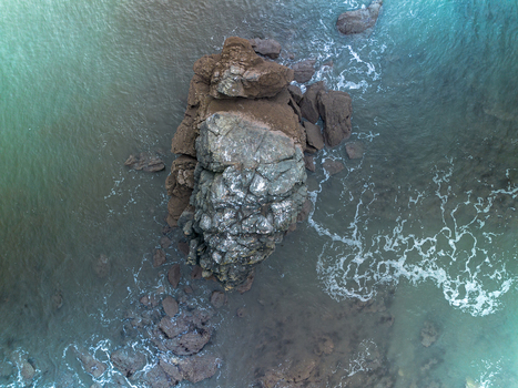 Aerial view of rugged rocks along the coastline surrounded by turquoise sea water Millendreath Cornwall United Kingdom. Aerial view of rugged rocks along the coastline surrounded by turquoise sea water Millendreath Cornwall United Kingdom.