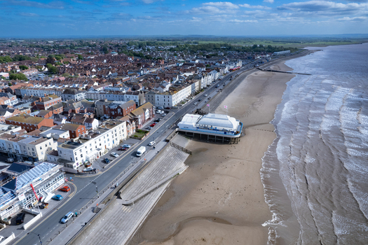 Aerial view of Burnham on Sea Pier extending over the sandy beach with historic town buildings a coastal road and the Bristol Channel in Burnham on Sea England United Kingdom. Aerial view of Burnham on Sea Pier extending over the sandy beach with historic town buildings a coastal road and the Bristol Channel in Burnham on Sea England United Kingdom.