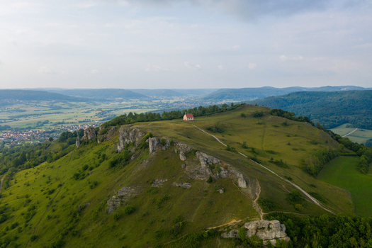 Aerial view of the Ehrenburg hill featuring the St. Walburgis chapel atop rocky cliffs and green slopes Leutenbach Bavaria Germany.