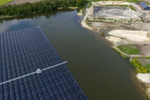 Aerial view of a large floating solar farm on a lake surrounded by green trees and industrial sand pits in Beilen Drenthe Netherlands. Aerial view of a large floating solar farm on a lake surrounded by green trees and industrial sand pits in Beilen Drenthe Netherlands.