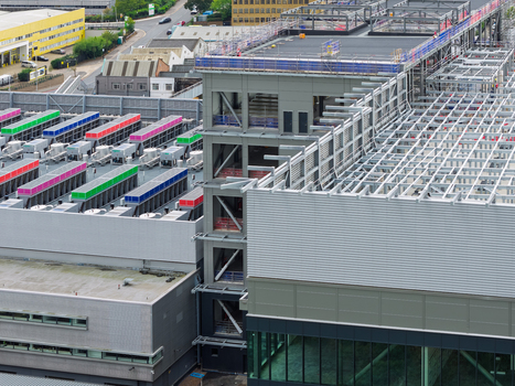 Aerial view of a large data center facility featuring industrial cooling units with colorful covers and steel framework in the United Kingdom.