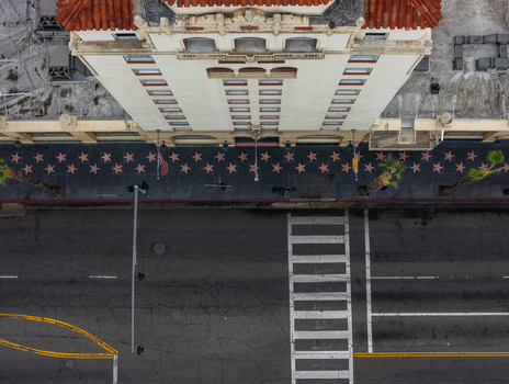 Aerial view of the Hollywood Walk of Fame with its iconic stars embedded in the sidewalk adjacent to a historic building facade and a crosswalk in Los Angeles California United States.