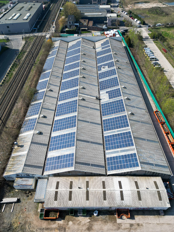 Aerial view of solar panels glinting atop a vast industrial roof reflecting the sky s soft light amidst the urban sprawl Ganshoren Brussels Belgium. Aerial view of solar panels glinting atop a vast industrial roof reflecting the sky s soft light amidst the urban sprawl Ganshoren Brussels Belgium.