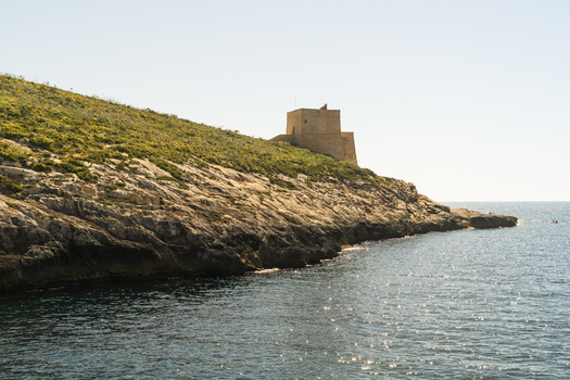 View of the historic Xlendi Tower standing on a rugged limestone cliff overlooking the Mediterranean Sea in Zebbug Gozo Region Malta.