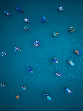 Aerial view of colorful traditional basket boats floating on the calm blue water in Vietnam. Aerial view of colorful traditional basket boats floating on the calm blue water in Vietnam.