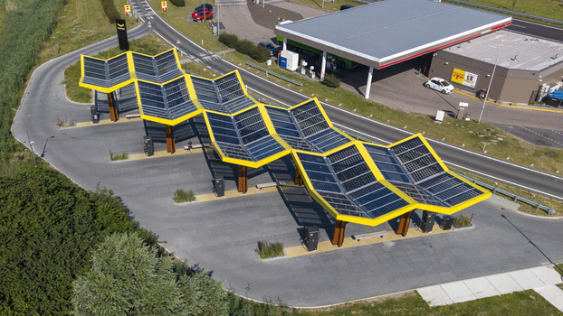 Aerial view of Fastned Charging Station with its distinctive yellow zigzag solar roof and electric vehicle chargers in Lelystad Flevoland Netherlands. Aerial view of Fastned Charging Station with its distinctive yellow zigzag solar roof and electric vehicle chargers in Lelystad Flevoland Netherlands.