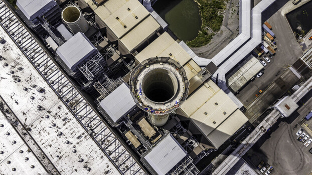 Aerial view of the exhaust stack at the fossil fuel power plant with industrial rooftops and infrastructure in Gallatin TN United States.