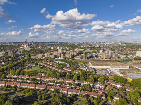 Aerial view of residential houses lush trees urban infrastructure and a distant skyline under a blue sky with clouds in Brentford England United Kingdom. Aerial view of residential houses lush trees urban infrastructure and a distant skyline under a blue sky with clouds in Brentford England United Kingdom.