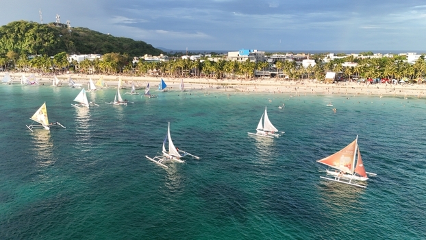 Malay Philippines 02 May 2026 Aerial view of Boracay Island with traditional paraw sailboats on turquoise water along the white sand beach and palm trees.
