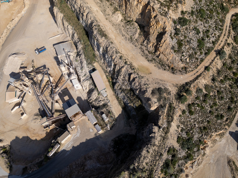 Aerial view of an industrial quarry site with stone crushing machinery conveyor belts and trucks situated in a rocky landscape in Teulada Valencian Community Spain.