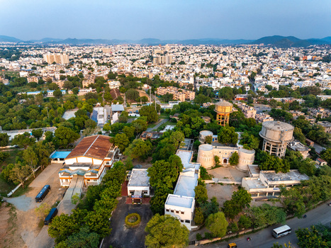 Aerial view of the urban landscape of Udaipur featuring water towers dense trees and residential buildings in Udaipur Rajasthan India. Aerial view of the urban landscape of Udaipur featuring water towers dense trees and residential buildings in Udaipur Rajasthan India.