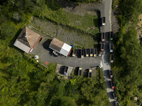 Aerial view of Tambang Pasir Merapi Kali Gendol Sand Mine with trucks parked near buildings surrounded by lush green forest Kecamatan Cangkringan Daerah Istimewa Yogya Indonesia. Aerial view of Tambang Pasir Merapi Kali Gendol Sand Mine with trucks parked near buildings surrounded by lush green forest Kecamatan Cangkringan Daerah Istimewa Yogya Indonesia.