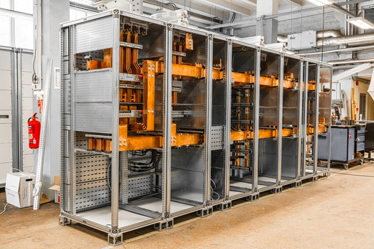 View of an industrial electrical switchgear cabinet with copper busbars and metal frame in a factory setting in Latvia. View of an industrial electrical switchgear cabinet with copper busbars and metal frame in a factory setting in Latvia.