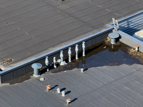 Aerial view of a flat roof featuring several ventilation pipes and areas of standing water in Leeuwarden Friesland Netherlands.