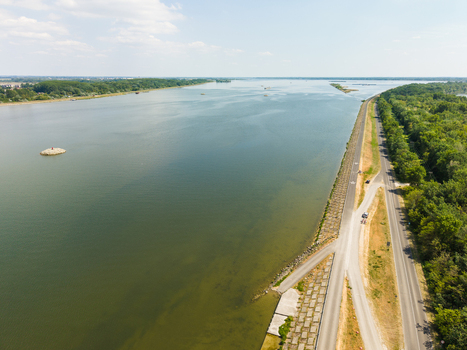 Aerial view of the Danube river with a paved cycling path and lush green forests along the banks under a bright sky in Bratislava Bratislava Region Slovakia. Aerial view of the Danube river with a paved cycling path and lush green forests along the banks under a bright sky in Bratislava Bratislava Region Slovakia.