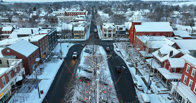 Aerial view of the snow covered town center with a star shaped holiday decoration historic brick buildings and cars driving on winter streets in Manheim Pennsylvania United States.