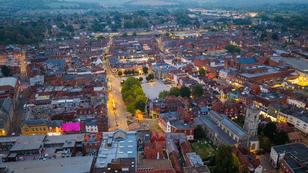 Aerial view of Salisbury Cathedral and the historic city center with red brick rooftops narrow streets and illuminated buildings at dusk in Salisbury England United Kingdom. Aerial view of Salisbury Cathedral and the historic city center with red brick rooftops narrow streets and illuminated buildings at dusk in Salisbury England United Kingdom.