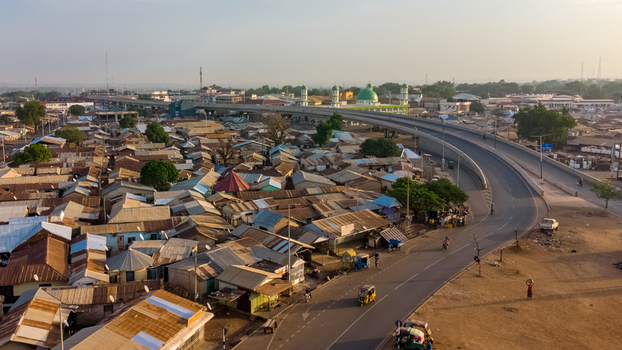 Aerial view of Tamale Interchange spanning over the residential area with metal rooftops and a mosque in the background in Tamale Northern Region Ghana.