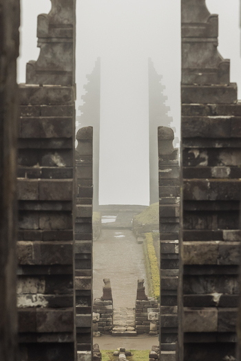 View of the iconic split gateway of Cetho Temple shrouded in thick mist with stone steps and ancient carvings Kecamatan Jenawi Jawa Tengah Indonesia. View of the iconic split gateway of Cetho Temple shrouded in thick mist with stone steps and ancient carvings Kecamatan Jenawi Jawa Tengah Indonesia.