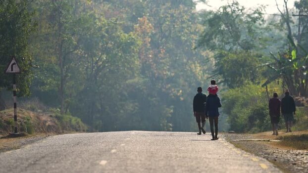 View of people walking along a road through a lush forest Nepal. View of people walking along a road through a lush forest Nepal.