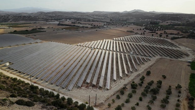 Aerial view of a large solar farm with rows of photovoltaic panels situated in a rural landscape with olive trees and rolling hills in Cyprus. Aerial view of a large solar farm with rows of photovoltaic panels situated in a rural landscape with olive trees and rolling hills in Cyprus.