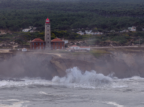 Aerial view of Farol Penedo da Saudade on rocky cliffs with crashing waves and a dense pine forest in Marinha Grande Leiria Portugal. Aerial view of Farol Penedo da Saudade on rocky cliffs with crashing waves and a dense pine forest in Marinha Grande Leiria Portugal.