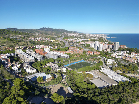 Aerial view of residential buildings a sports field and lush greenery along the Mediterranean coastline in Montgat Catalonia Spain. Aerial view of residential buildings a sports field and lush greenery along the Mediterranean coastline in Montgat Catalonia Spain.