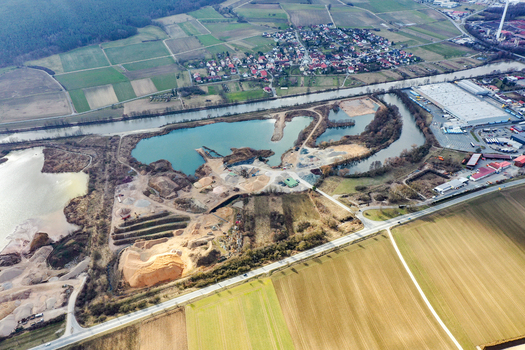 Aerial view of a gravel pit with turquoise water ponds industrial machinery and surrounding agricultural fields in Forchheim Bavaria Germany. Aerial view of a gravel pit with turquoise water ponds industrial machinery and surrounding agricultural fields in Forchheim Bavaria Germany.