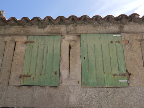 View of a traditional stone horreo with weathered green wooden shutters and terracotta roof tiles in Combarro Pontevedra Spain.