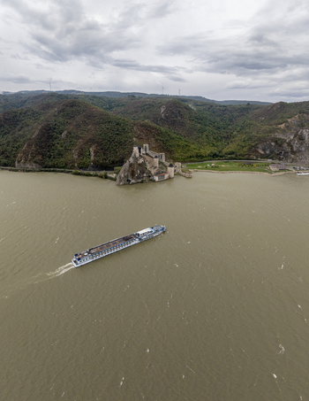 Aerial view of the historic Golubac Fortress situated on the banks of the Danube river with a river cruise ship sailing past under a cloudy sky in Golubac Branicevski Okrug Serbia. Aerial view of the historic Golubac Fortress situated on the banks of the Danube river with a river cruise ship sailing past under a cloudy sky in Golubac Branicevski Okrug Serbia.