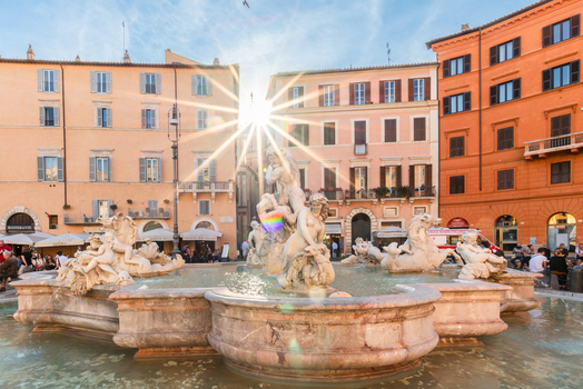 View of the Fountain of the Four Rivers in Piazza Navona with a sunburst effect behind historic buildings in Rome Lazio Italy. View of the Fountain of the Four Rivers in Piazza Navona with a sunburst effect behind historic buildings in Rome Lazio Italy.