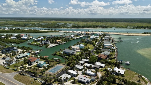 Aerial view of Matanzas Inlet featuring waterfront residential homes canals a tennis court and lush coastal vegetation in St. Johns County Florida United States. Aerial view of Matanzas Inlet featuring waterfront residential homes canals a tennis court and lush coastal vegetation in St. Johns County Florida United States.