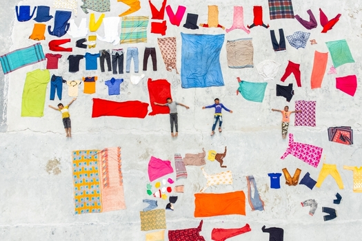 Dinajpur District Bangladesh 26 July 2026 Aerial view of Jharbari Bazar with children lying on a concrete surface surrounded by colorful drying laundry.