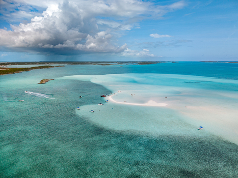 Aerial view of Man O War Cay Sandbar with boats anchored in turquoise waters under a cloudy sky near Rolletown Exuma The Bahamas. Aerial view of Man O War Cay Sandbar with boats anchored in turquoise waters under a cloudy sky near Rolletown Exuma The Bahamas.