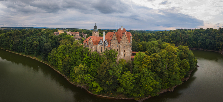 Aerial view of Czocha Castle surrounded by dense green forests and the winding Kwisa River under a cloudy sky in Sucha Dolnoslaskie Poland. Aerial view of Czocha Castle surrounded by dense green forests and the winding Kwisa River under a cloudy sky in Sucha Dolnoslaskie Poland.
