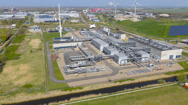 Aerial view of the Boekelermeer industrial facility featuring complex piping systems solar panels and wind turbines under a clear blue sky in Alkmaar Noord Holland Netherlands. Aerial view of the Boekelermeer industrial facility featuring complex piping systems solar panels and wind turbines under a clear blue sky in Alkmaar Noord Holland Netherlands.