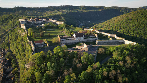 Aerial view of the historic Besancon Citadel with its massive stone fortifications and lush green hills under a clear sky in Besancon Bourgogne Franche Comte France. Aerial view of the historic Besancon Citadel with its massive stone fortifications and lush green hills under a clear sky in Besancon Bourgogne Franche Comte France.