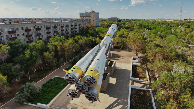 Aerial view of the Soyuz rocket monument at Baikonur Cosmodrome surrounded by lush green trees and residential buildings in Karmakshy District Kyzylorda Region Kazakhstan.