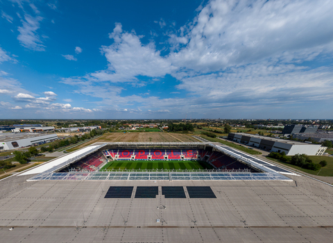 Opole Poland 09 September 2026 Aerial view of Itaka Arena stadium with its green pitch red seating and surrounding industrial area under a blue sky with scattered clouds. Opole Poland 09 September 2026 Aerial view of Itaka Arena stadium with its green pitch red seating and surrounding industrial area under a blue sky with scattered clouds.