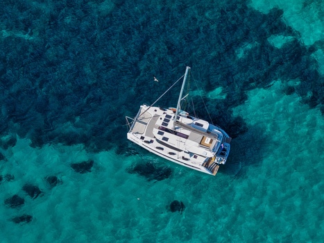 Aerial view of a white catamaran sailing in the clear turquoise waters off the coast of Ile Sainte Marguerite Cannes Provence Alpes Cote d Azur France. Aerial view of a white catamaran sailing in the clear turquoise waters off the coast of Ile Sainte Marguerite Cannes Provence Alpes Cote d Azur France.
