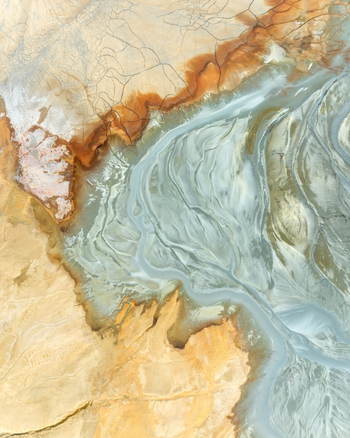 Aerial view of the abstract patterns and mineral deposits at the Minas de Riotinto mining site with reddish orange soil and grey flowing textures Minas de Riotinto Andalusia Spain.