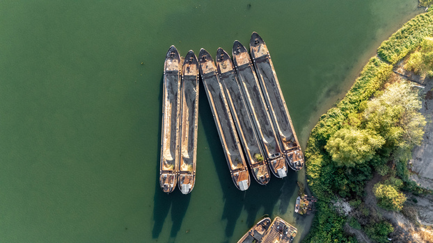 Aerial view of cargo barges moored in the Sava River near the riverbank with lush trees in Sremska Mitrovica Vojvodina Serbia.