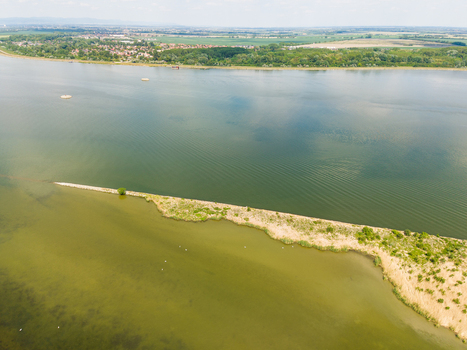 Aerial view of the Danube river featuring a long sandy breakwater and lush green banks in Bratislava Bratislava Region Slovakia. Aerial view of the Danube river featuring a long sandy breakwater and lush green banks in Bratislava Bratislava Region Slovakia.