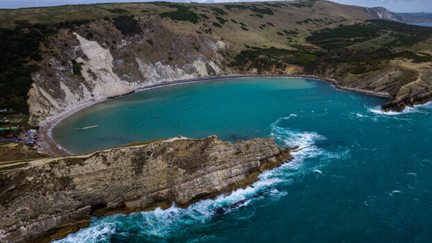 Aerial view of Lulworth Cove showing the turquoise bay dramatic limestone cliffs and rugged coastline in Wareham England United Kingdom. Aerial view of Lulworth Cove showing the turquoise bay dramatic limestone cliffs and rugged coastline in Wareham England United Kingdom.