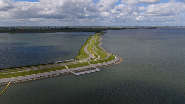 Aerial view of a winding road on a grassy dike surrounded by the waters of Markermeer in Uitdam North Holland Netherlands.