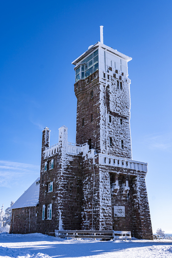 View of a snow kissed stone tower piercing the azure sky its frosted windows reflecting the winter sun in Sasbach Baden Württemberg Germany. View of a snow kissed stone tower piercing the azure sky its frosted windows reflecting the winter sun in Sasbach Baden Württemberg Germany.